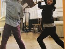 Michelle Gomez swinging a chair in the theatre programme for The Taming of the Shrew